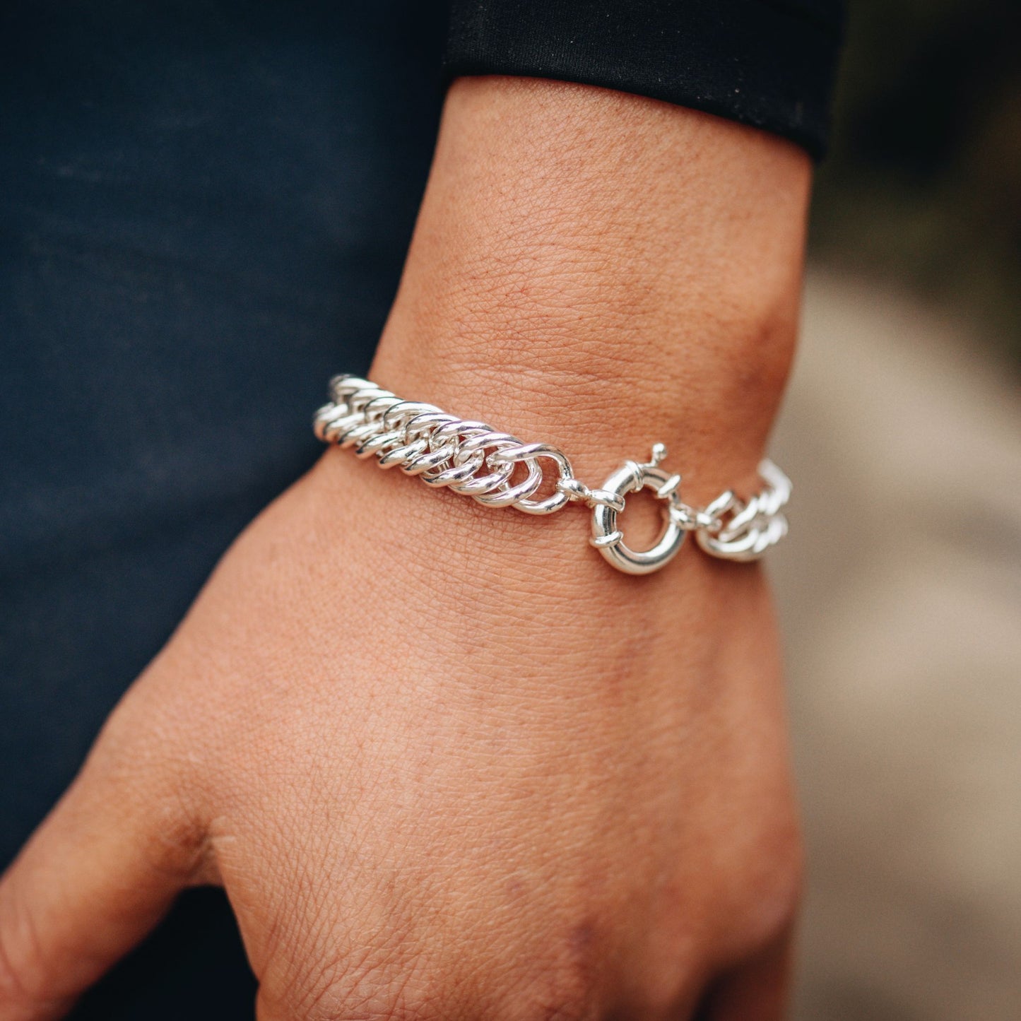 Silver curb chain horse bracelet on a wrist with a blurred background. Made by Crawford Hill Equestrian Jewellery.