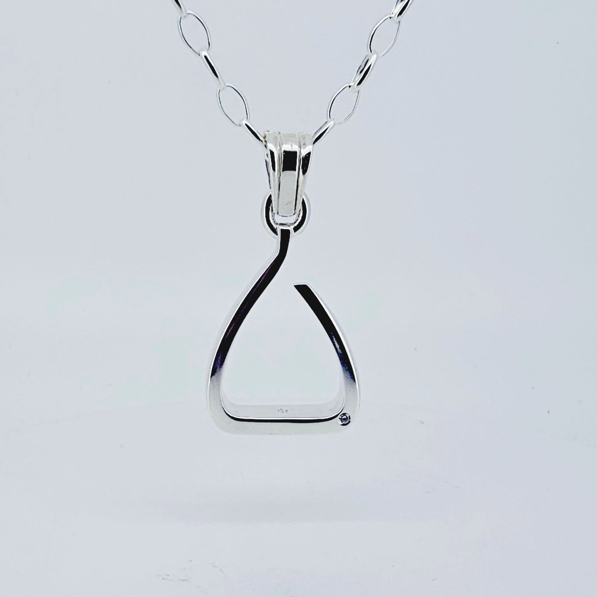 Product shot. Silver jump stirrup necklace. Set with one diamond. Based on the Freejump Stirrup. This is for Horse riders and equestrians. Made by Crawford Hill Equestrian Jewellery.